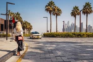 Frau steht auf der Straße und wartet auf ein Taxi.