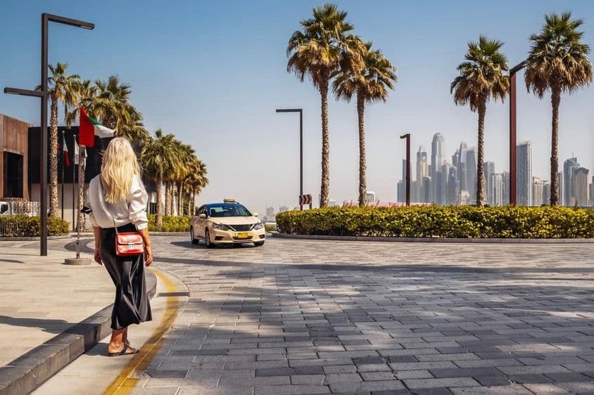 Frau steht auf der Straße und wartet auf ein Taxi.