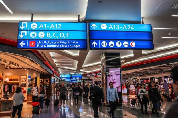 Passagiere gehen in Richtung der Abflugsteige am Dubai International Airport