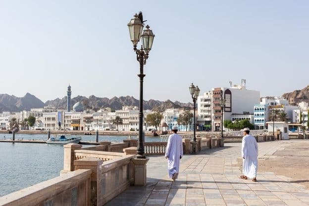 Männer in traditioneller omanischer Tracht entlang der Uferpromenade von Maskat.