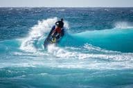 Jetski trifft auf das Wasser über einer brechenden Welle