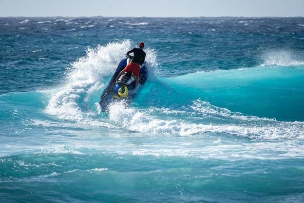 Jetski trifft auf das Wasser über einer brechenden Welle