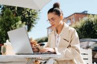 Stilvolle Geschäftsfrau mit Brille arbeitet an einem Laptop